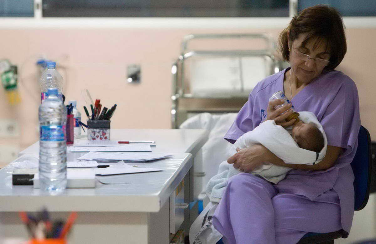 Personal de Enfermería de la Sala de Neonatología alimenta con biberón a un recién nacido